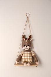 Photo of Shelf with cute toy deer on beige wall. Child's room interior element