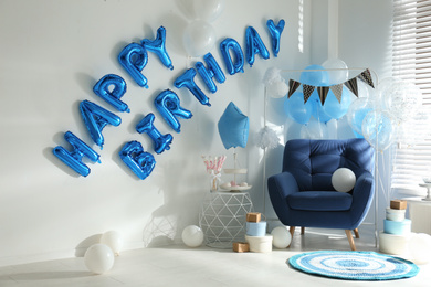 Photo of Phrase HAPPY BIRTHDAY made of blue balloon letters in decorated room