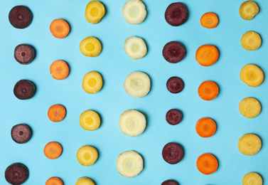 Photo of Slices of raw color carrots on light blue background, flat lay