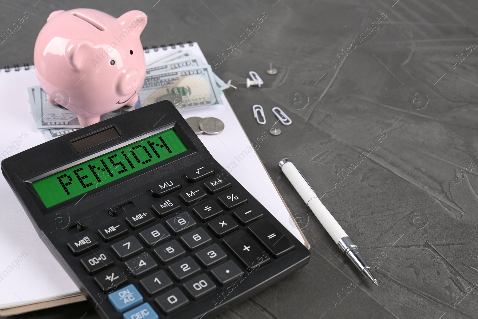 Image of Calculator with word Pension, piggy bank, money and stationery on grey table, closeup