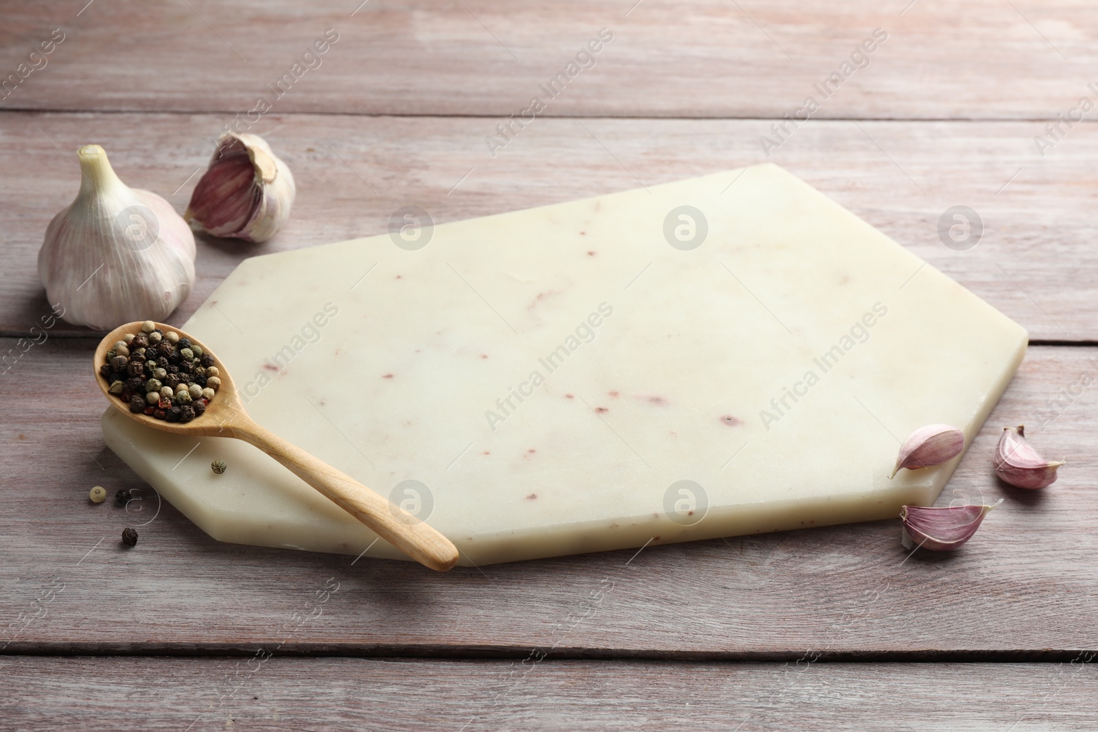 Photo of Cutting board, pepper and garlic on light wooden table. Space for text