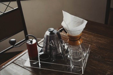 Photo of Coffee maker, grinder and kettle on wooden table in cafe