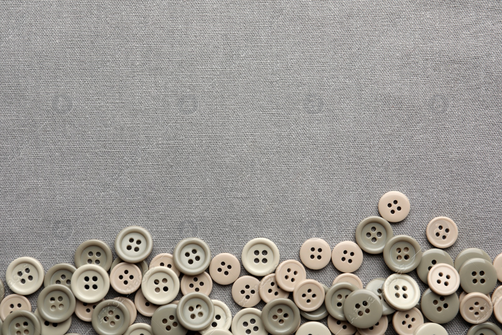 Photo of Many plastic sewing buttons on grey fabric, flat lay. Space for text