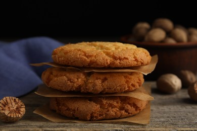 Tasty cookies and nutmeg seeds on wooden table, closeup