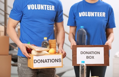 Photo of Volunteers holding donation boxes with food products indoors