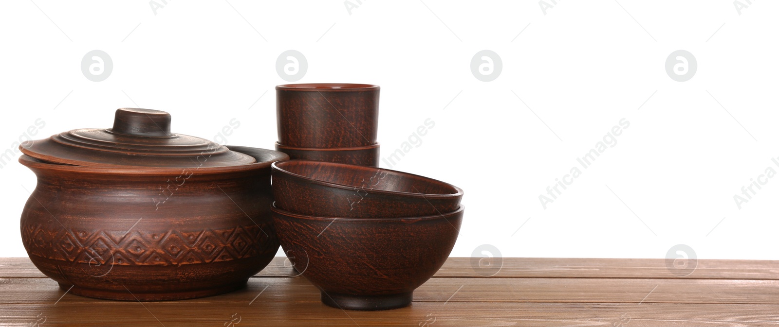 Photo of Set of stylish clay dishes on wooden table against white background. Space for text