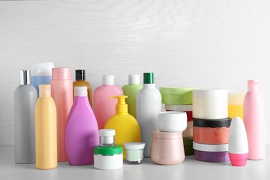 Photo of Different body care products on table against light wooden background