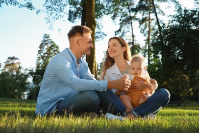 Parents with their cute daughter spending time together in park on summer day