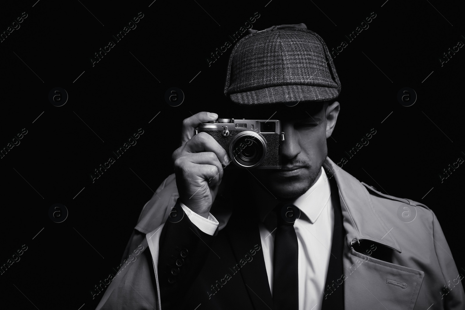 Photo of Old fashioned detective with camera on dark background, black and white effect