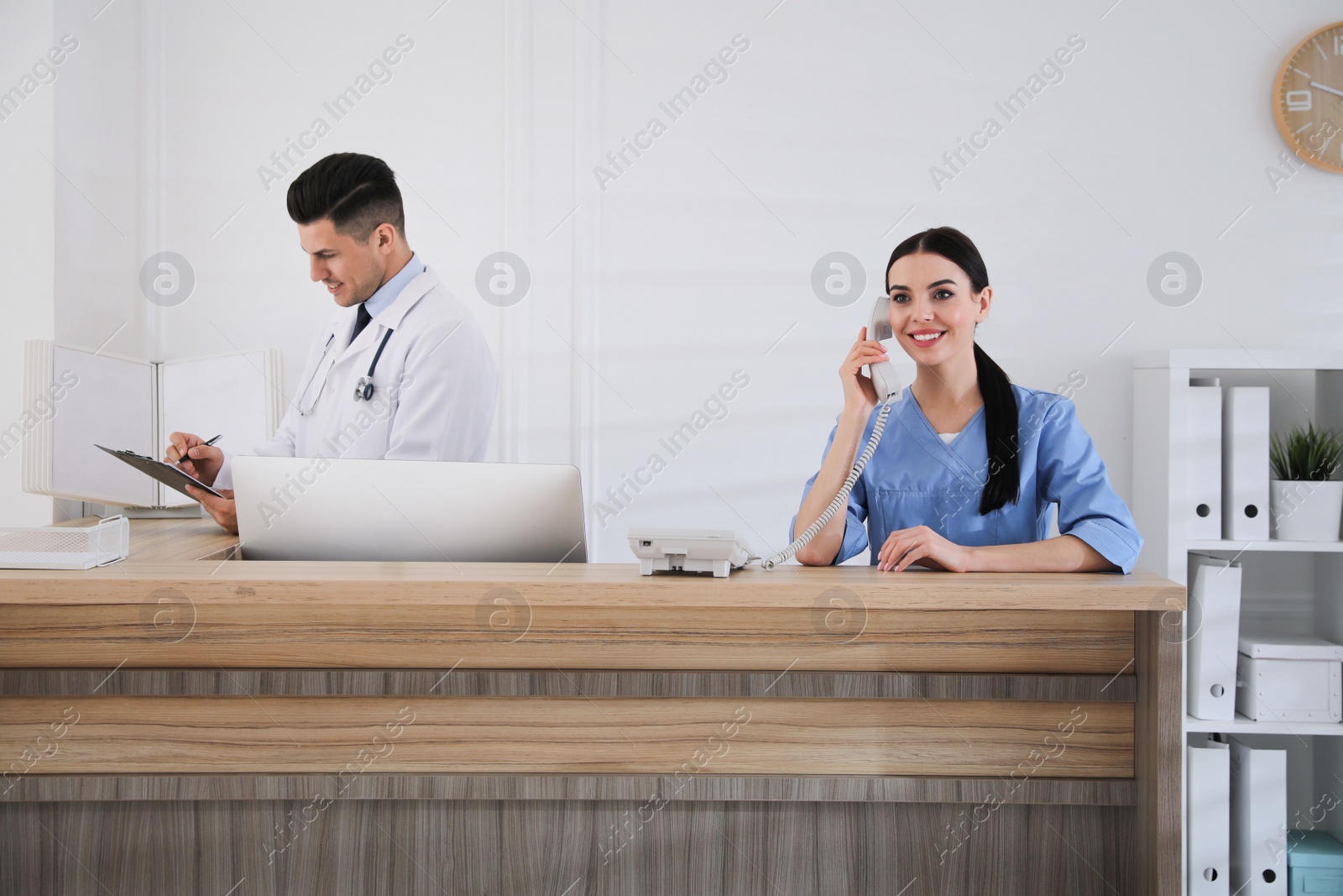 Photo of Receptionist and doctor working at countertop in hospital