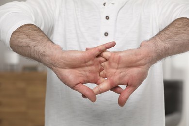 Photo of Man cracking his knuckles on blurred background, closeup. Bad habit