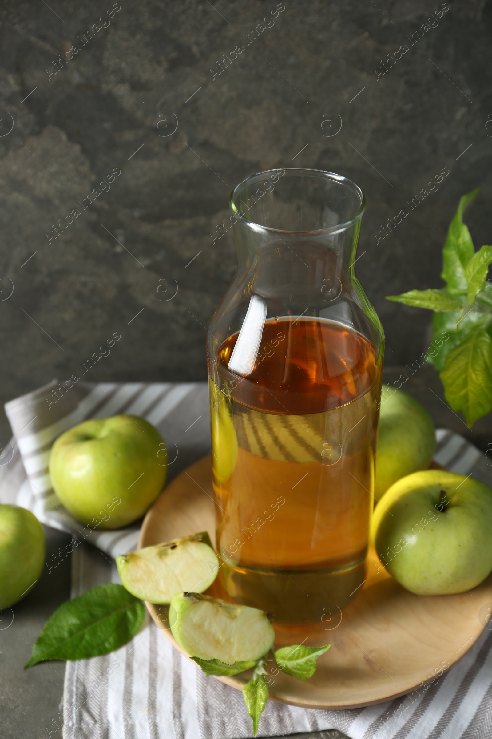 Photo of Delicious cider, ripe apples and green leaves on gray table