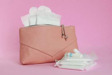 Bag with menstrual pads and tampons on pink background
