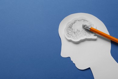Photo of Human head cutout with erased brain and pencil on blue background, space for text. Dementia concept