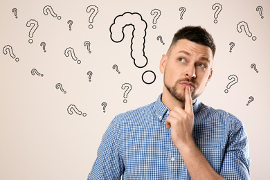 Image of Emotional man with drawings of question marks on white background