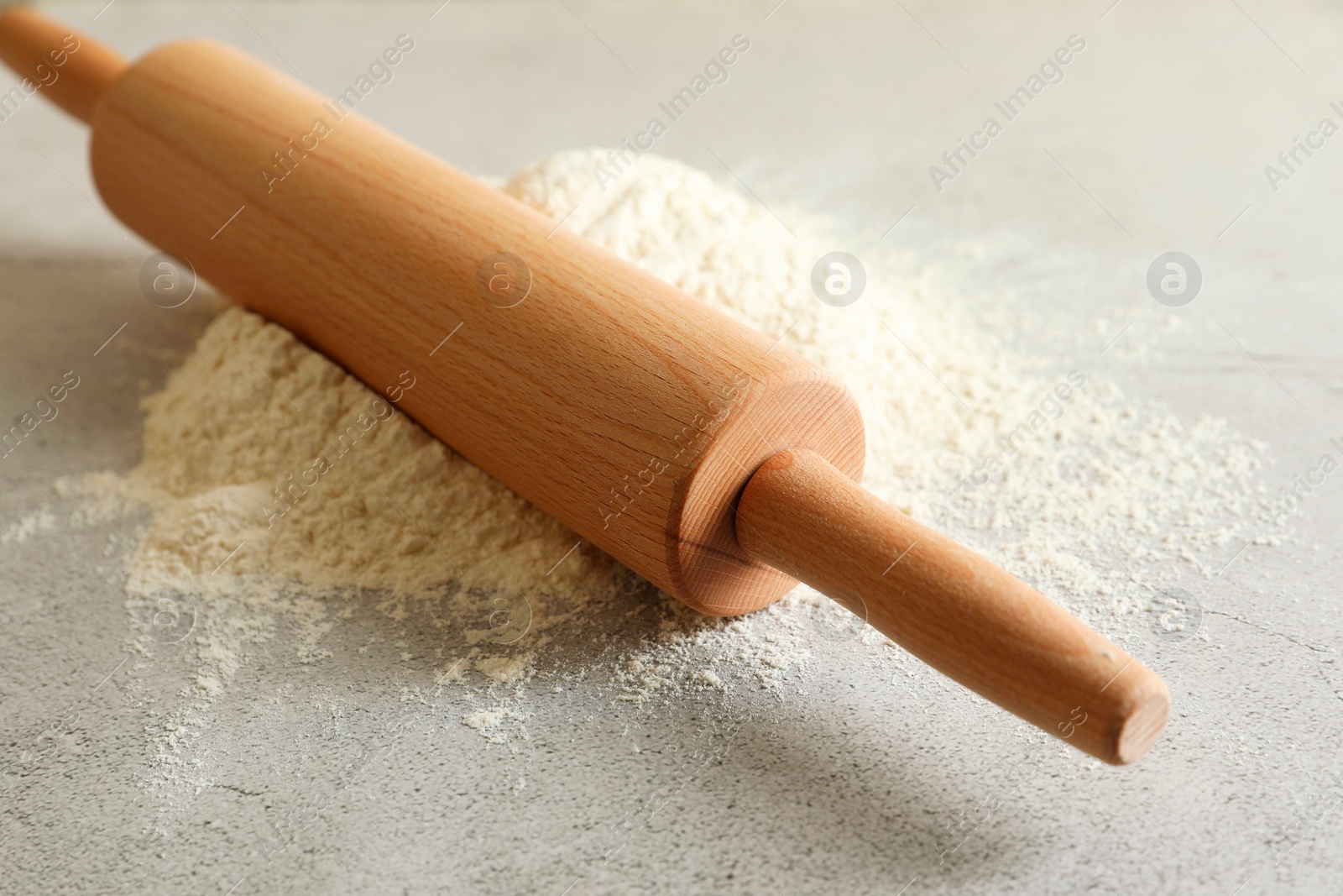 Photo of Flour and rolling pin on grey table, closeup