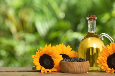 Sunflower cooking oil, seeds and yellow flowers on wooden table outdoors, space for text