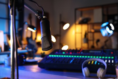 Photo of Microphone near table with professional mixing console in radio studio