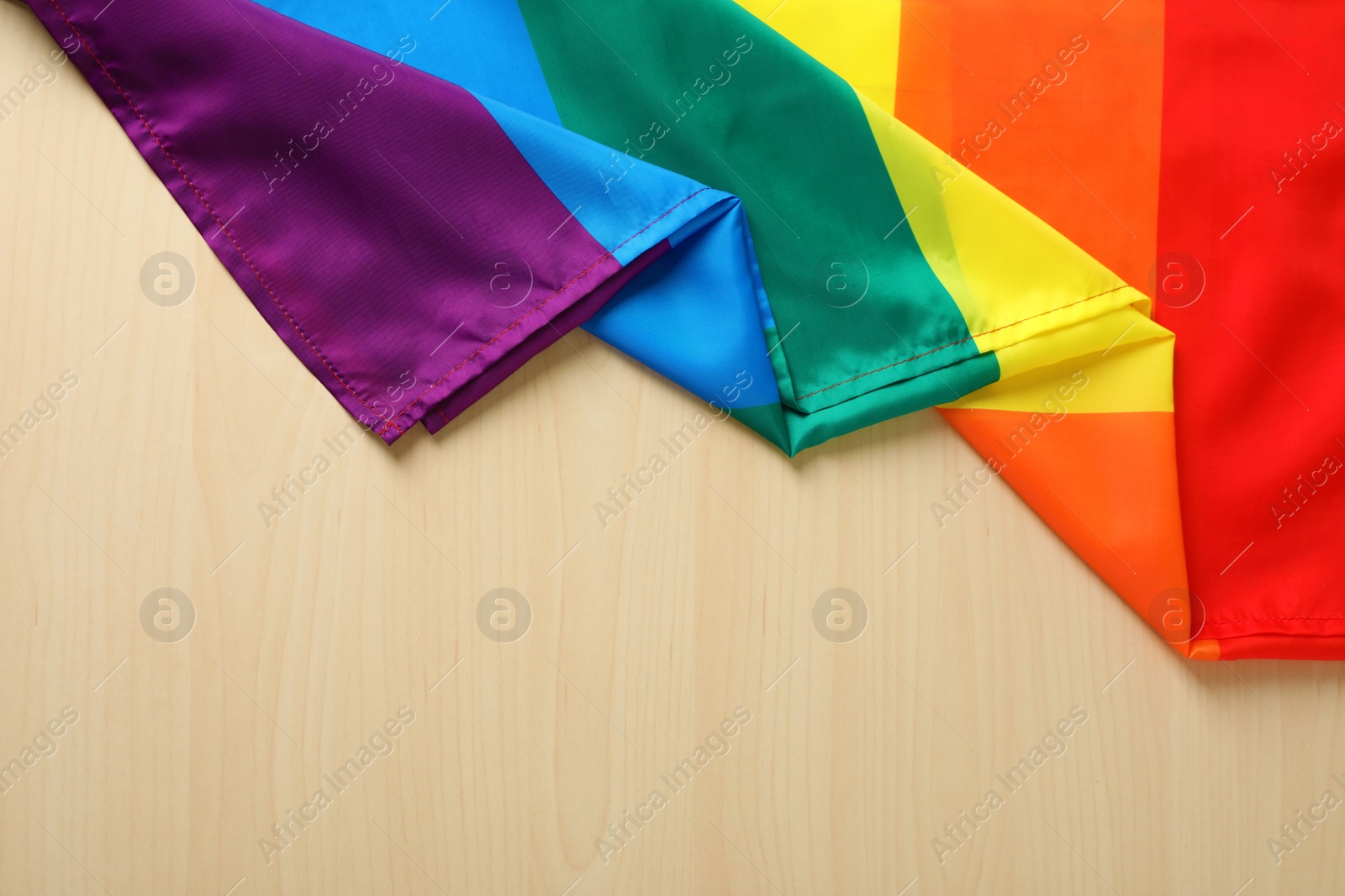 Photo of Rainbow gay flag on wooden background, top view with space for text. LGBT concept