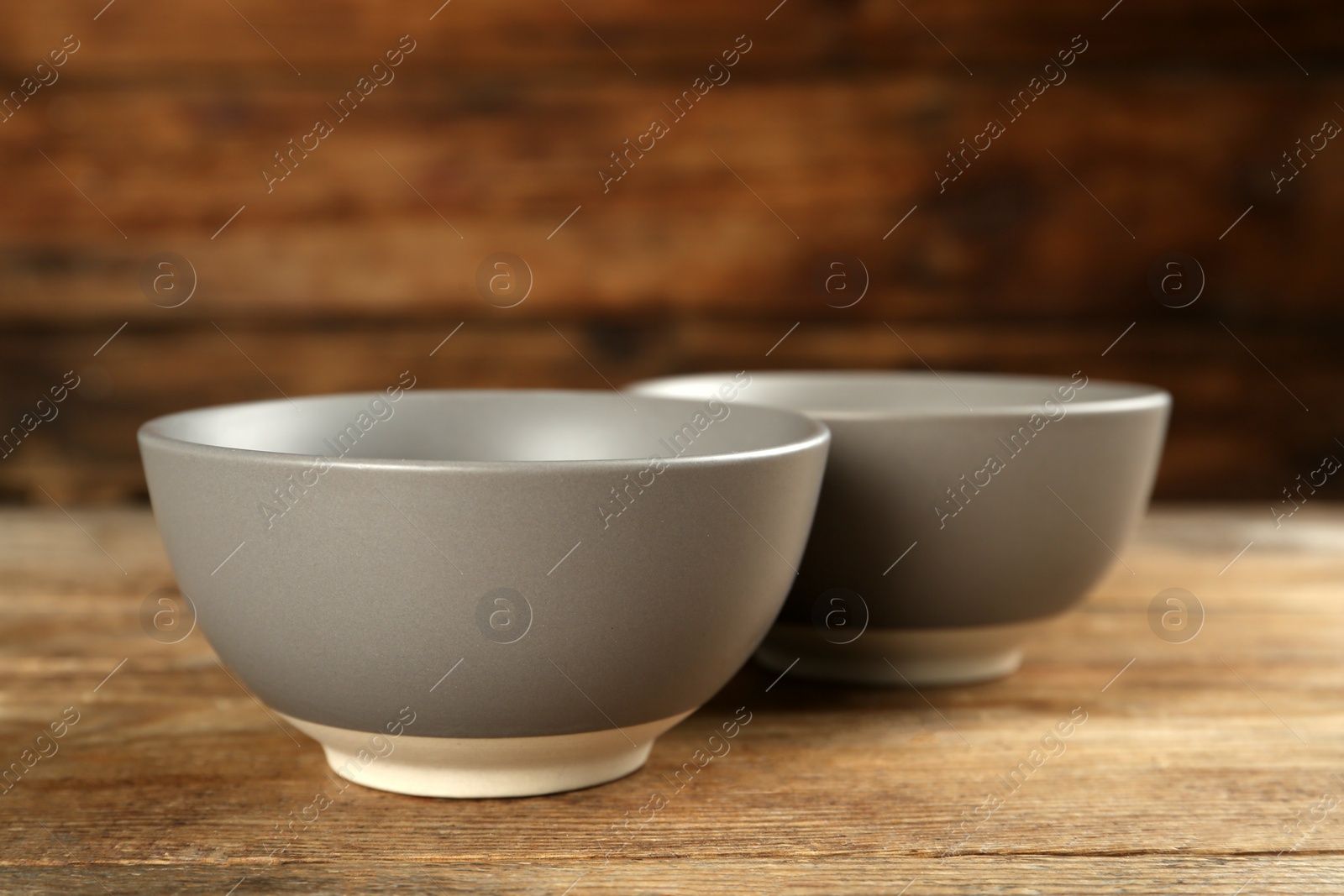 Photo of Stylish empty ceramic bowls on wooden table. Cooking utensils