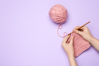 Photo of Woman crocheting with pink thread on violet background, top view. Space for text