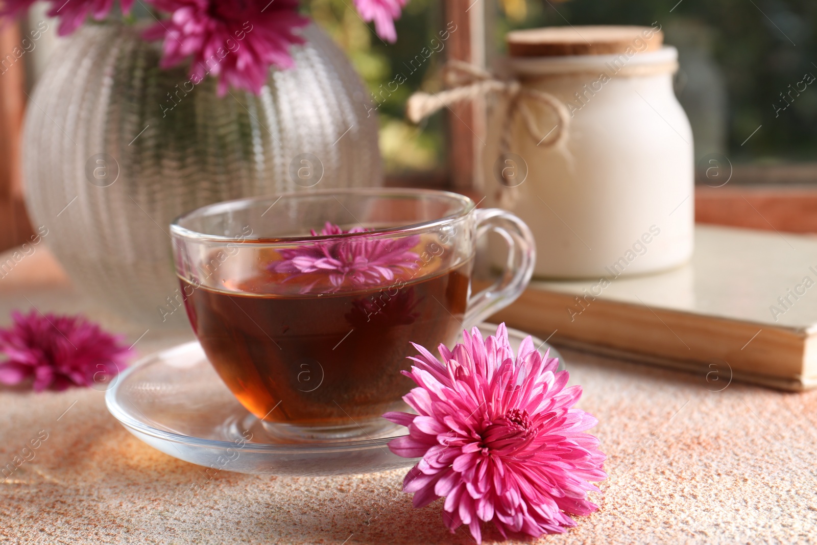 Photo of Beautiful chrysanthemum flowers and cup of tea on beige textured table. Autumn still life