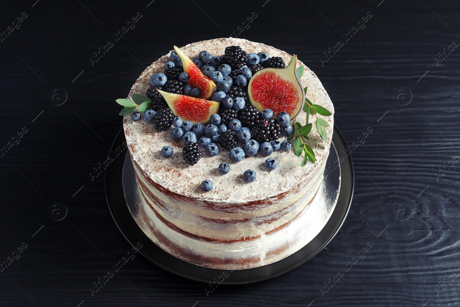 Photo of Delicious homemade cake with fresh berries on dark wooden table