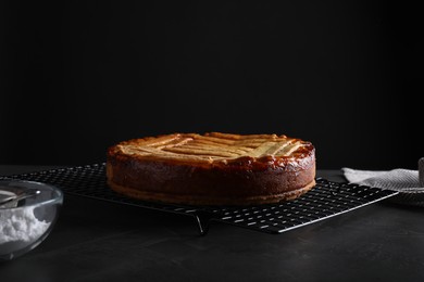 Photo of Tasty apricot pie on table against black background