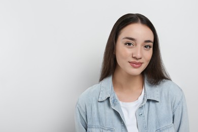 Photo of Portrait of beautiful young woman in jeans jacket on white background. Space for text