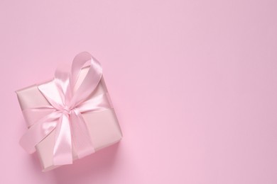 Beautiful gift box with bow on pink background, top view. Space for text