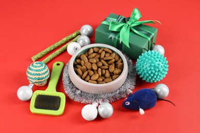 Photo of Different pet goods with Christmas gift on red background. Shop assortment