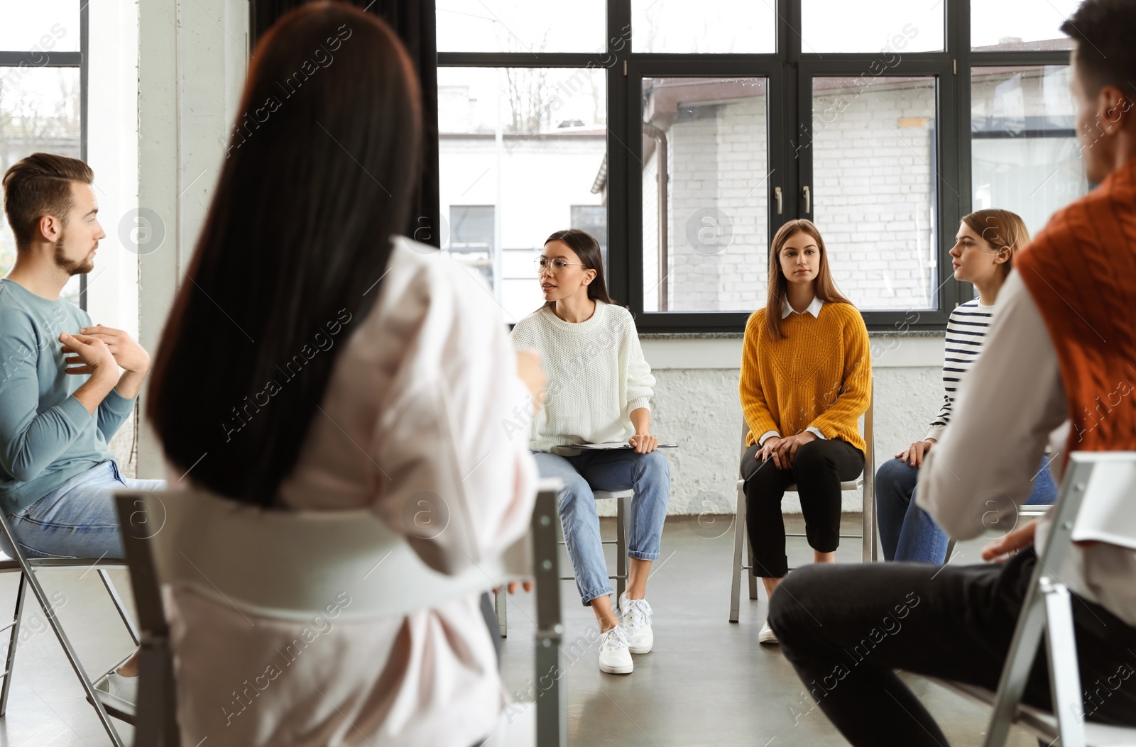 Photo of Psychotherapist working with patients in group therapy session indoors