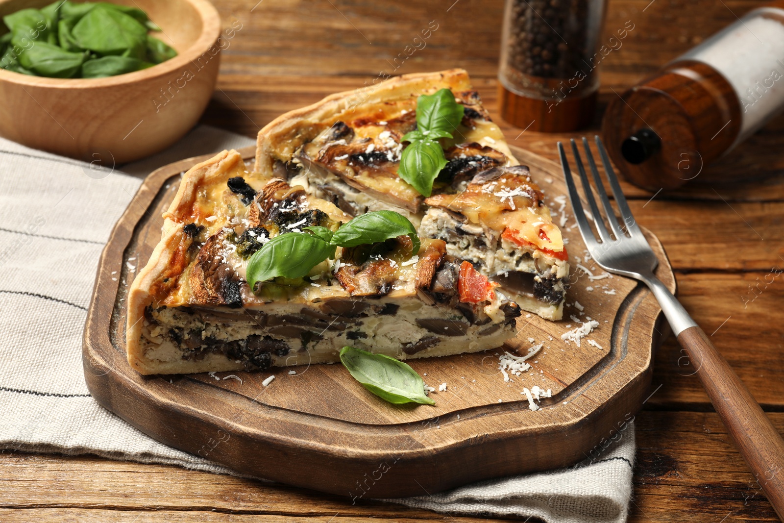 Photo of Pieces of delicious quiche with mushrooms served on wooden table, closeup