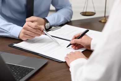 Lawyers working with documents at wooden table indoors, closeup