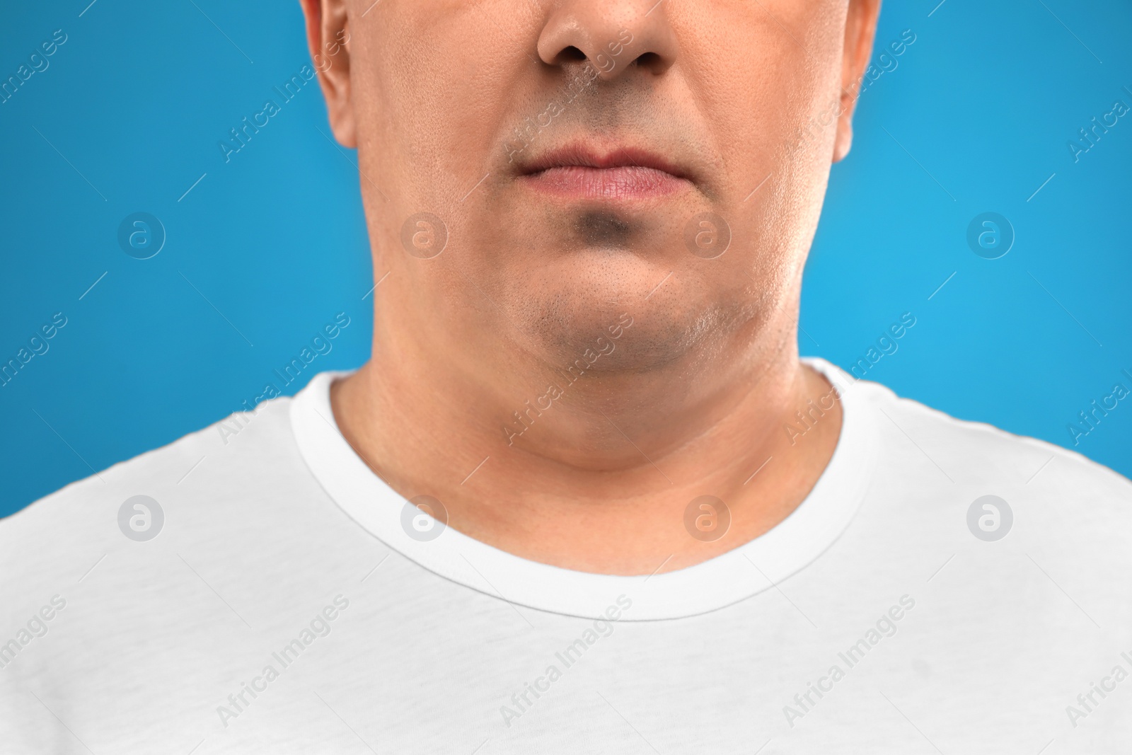 Photo of Mature man with double chin on blue background, closeup