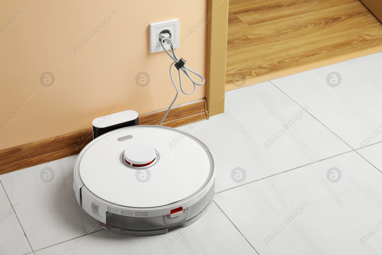 Photo of Robotic vacuum cleaner charging on white floor indoors