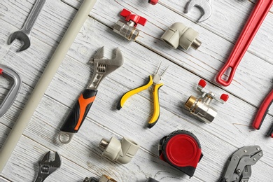 Flat lay composition with plumber's tools on white wooden background