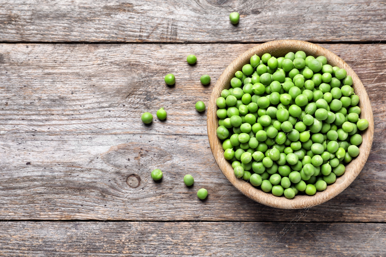 Photo of Bowl with delicious fresh green peas on wooden table, top view