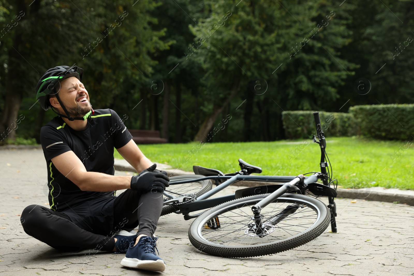 Photo of Man with injured knee near bicycle outdoors