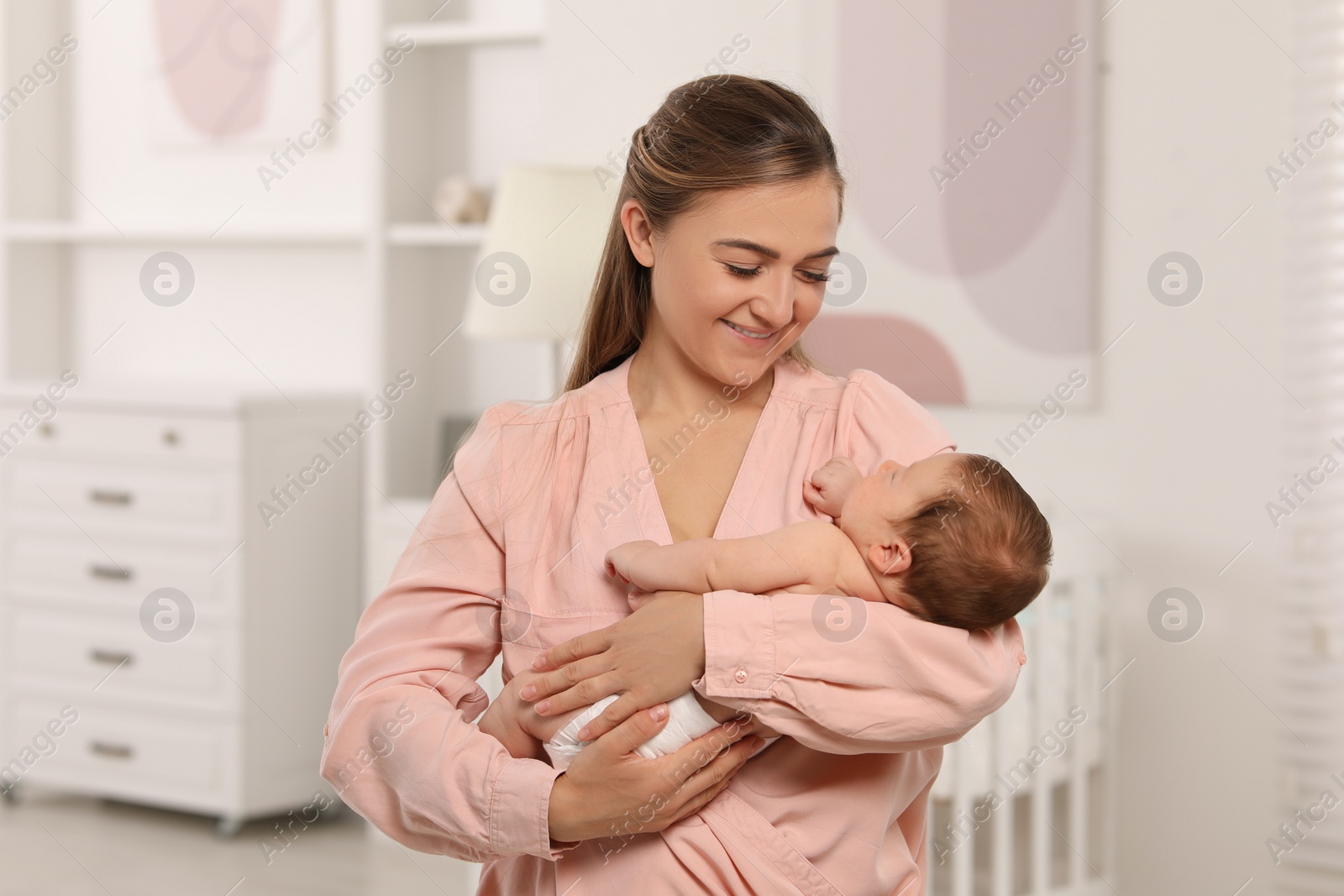 Photo of Mother holding her cute newborn baby in child's room