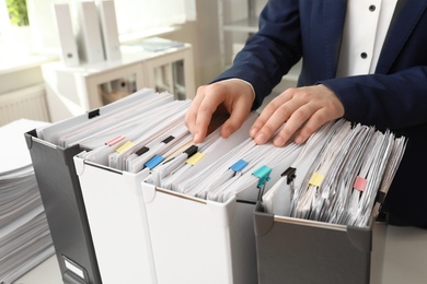 Woman taking documents from folder in archive, closeup