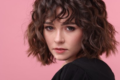 Beautiful young woman with wavy hairstyle on pink background