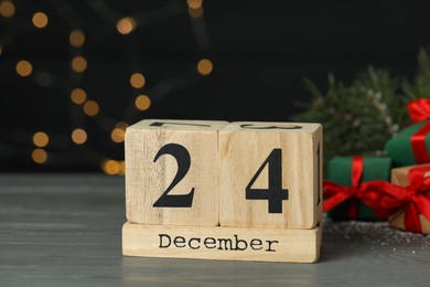Photo of December 24 - Christmas Eve. Wooden block calendar and decor on table against blurred festive lights