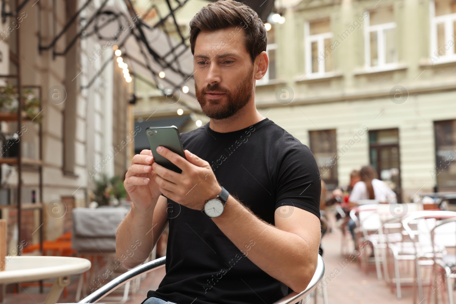 Photo of Handsome man using smartphone in outdoor cafe
