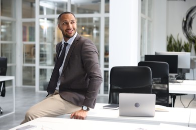 Happy man sitting on table in office. Lawyer, businessman, accountant or manager
