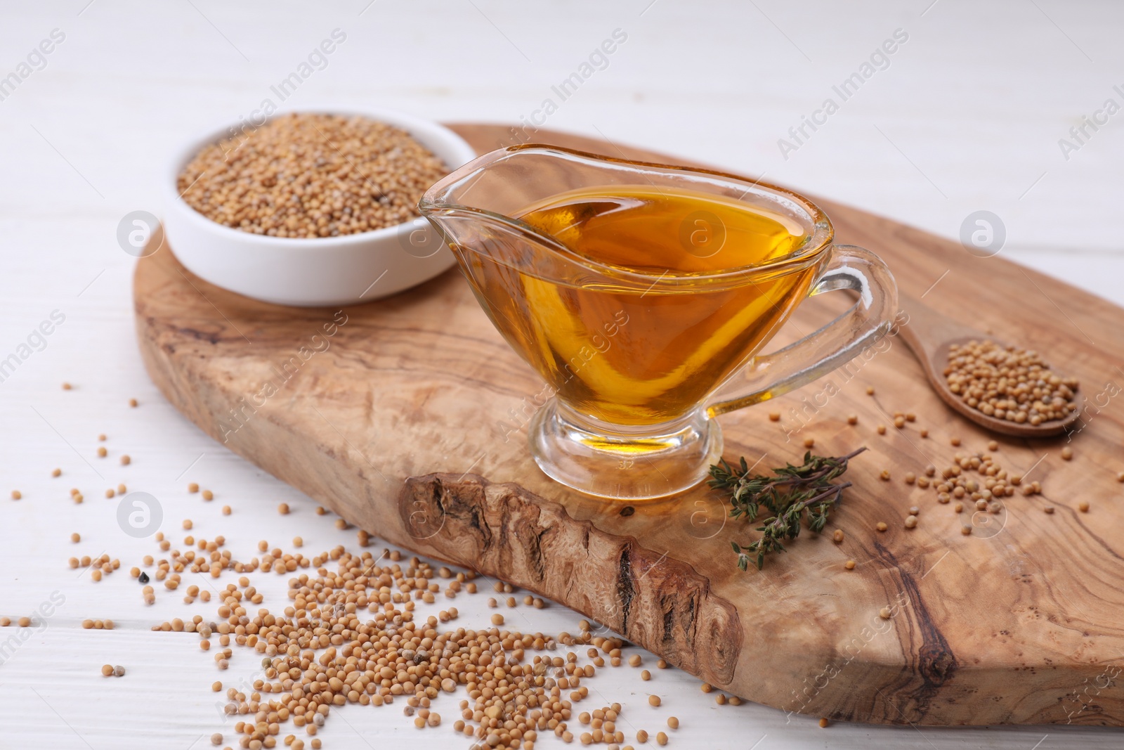 Jug of natural oil and mustard seeds on white wooden table Photo of Jug of natural oil and mustard seeds on white wooden table