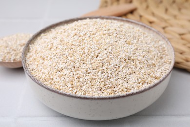 Photo of Raw barley groats in bowl on light table, closeup