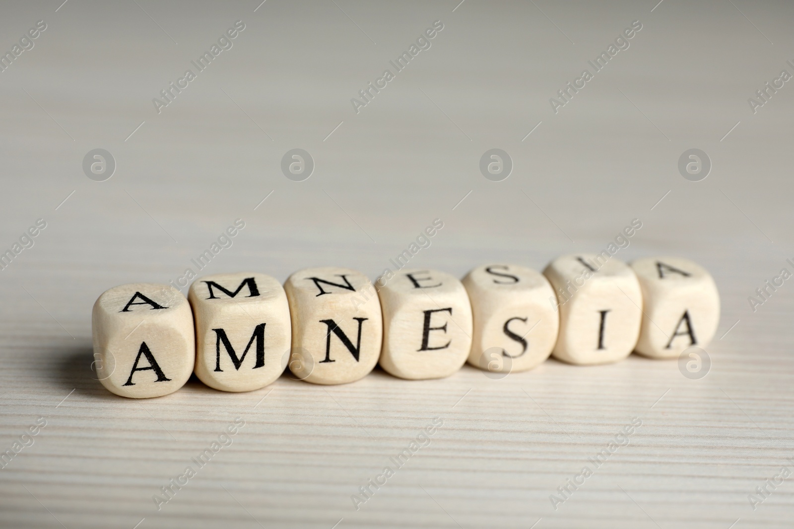 Photo of Cubes with word Amnesia on white wooden table, closeup view