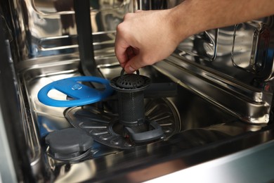 Photo of Repairman pulling drain filter out of dishwasher, closeup