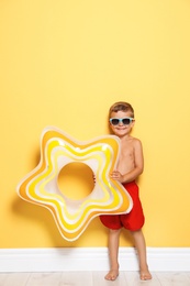 Photo of Cute little boy with bright star shaped inflatable ring near color wall